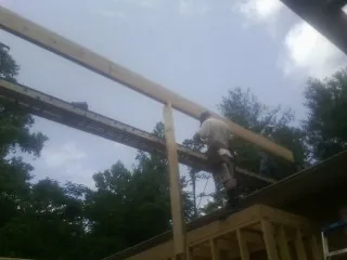Carpenter setting a ridge beam over a new addition frame — Ice Dam Removal by Roofing Brothers in Amherst