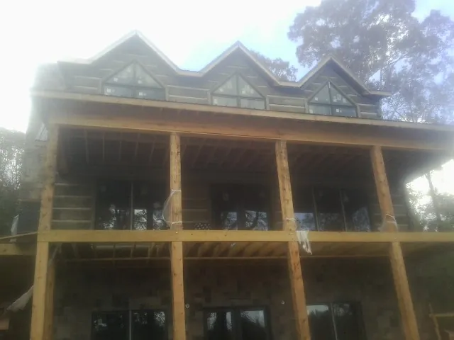 Dormers and porch framing on a large log home under construction — Roof Coating work by our crew in Amherst